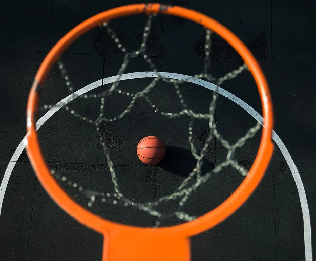 Overhead perspective through a basketball rim showing a ball positioned on the court below.